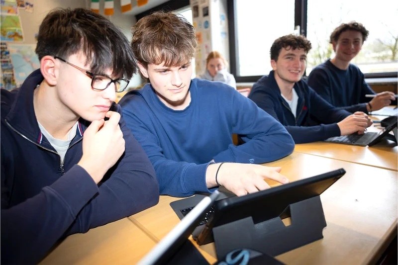 Zwei Schüler sitzen zusammen und lösen am Laptop eine Aufgabe.