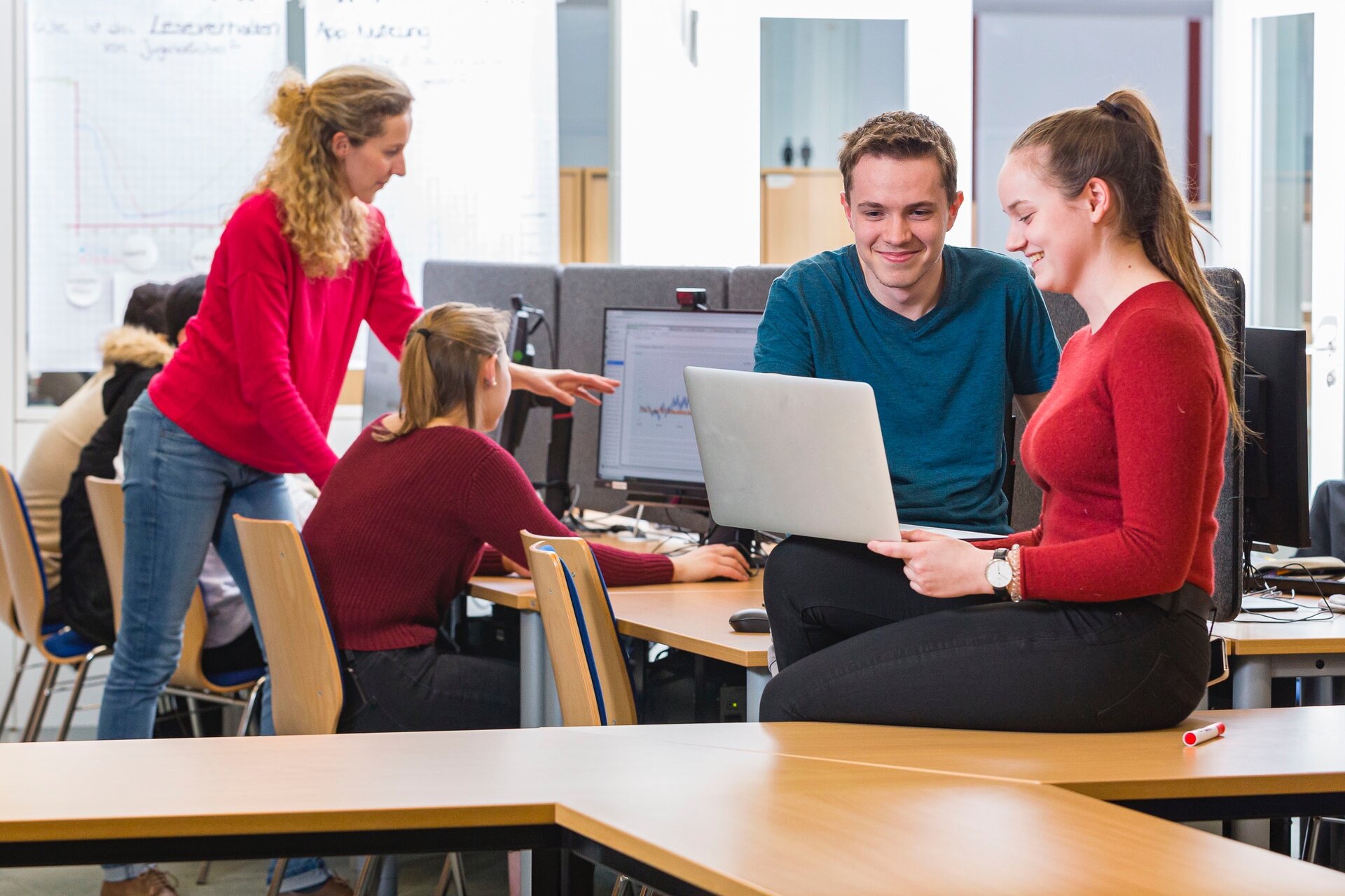 Drei Erwachsene arbeiten gemeinsam auf einer Bürofläche.