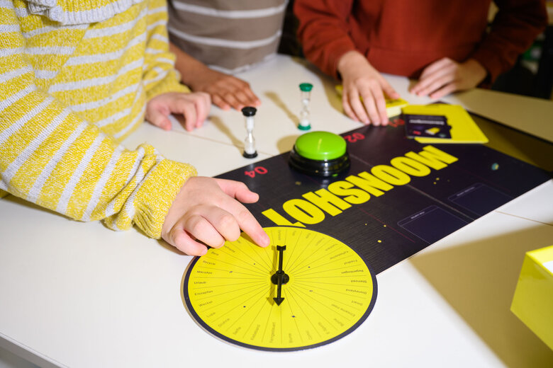 Hände von Schüler*innen auf einem Tisch, die das Spiel Moonshot EDU spielen.