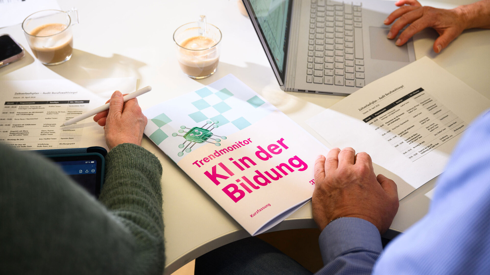 Der "Trendmonitor KI in der Bildung" liegt auf einem Schreibtisch. Eine Hand blättert.