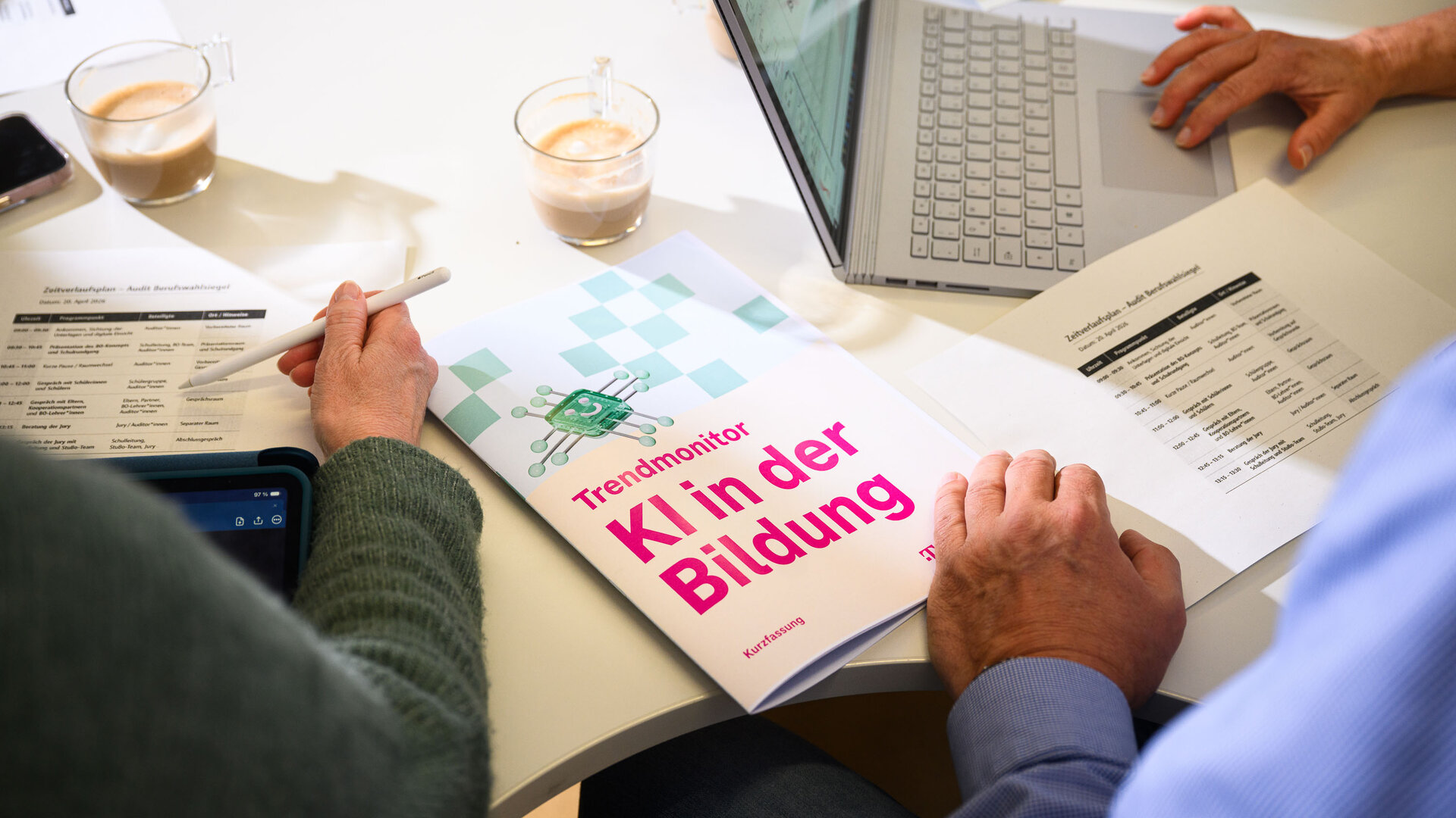 Der "Trendmonitor KI in der Bildung" liegt auf einem Schreibtisch. Eine Hand blättert.