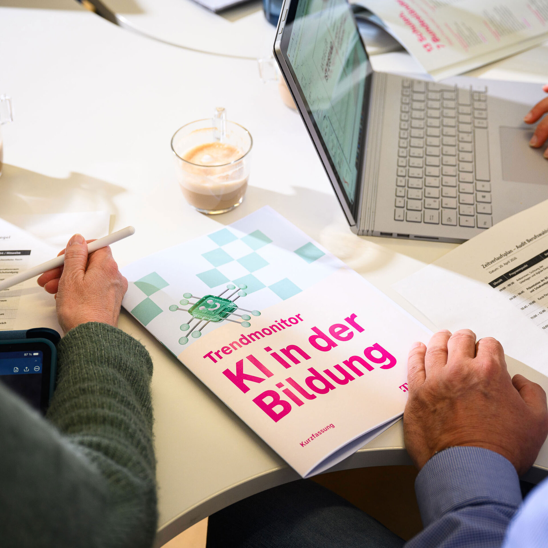 Der "Trendmonitor KI in der Bildung" liegt auf einem Schreibtisch. Eine Hand blättert.