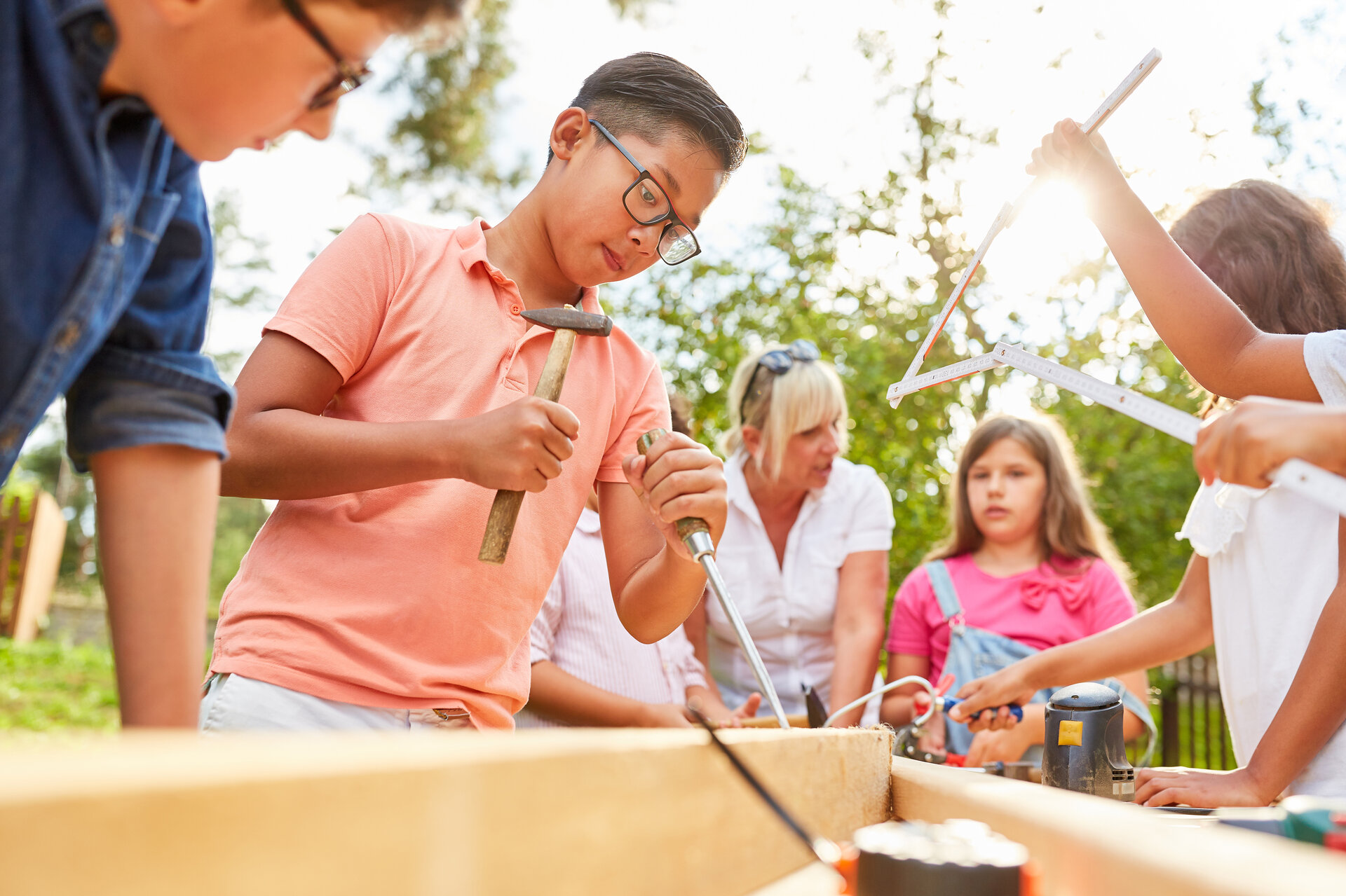 Kinder arbeiten gemeinsam draußen an einer Werkbank.