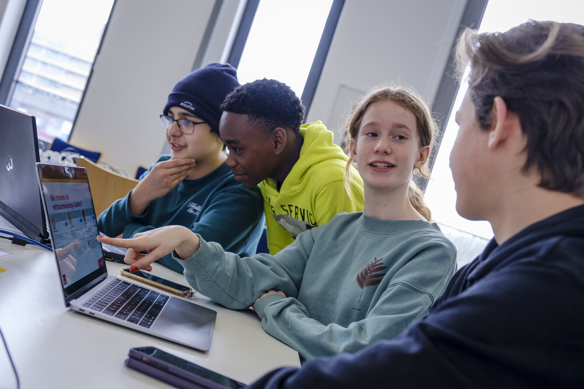 Jugendliche arbeiten gemeinsam an Laptops.