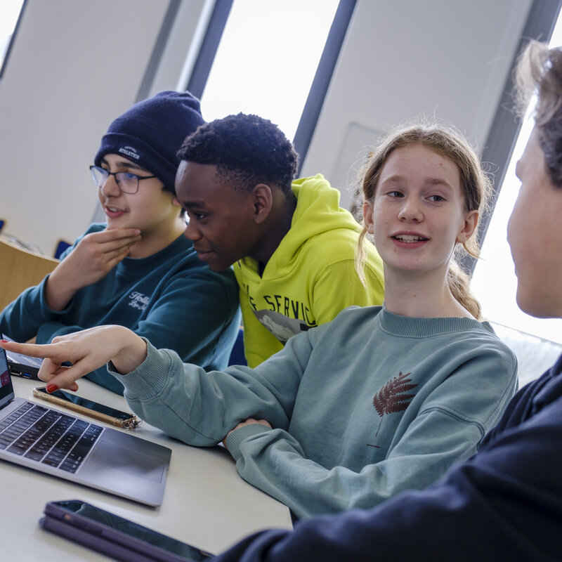 Jugendliche arbeiten gemeinsam an Laptops.