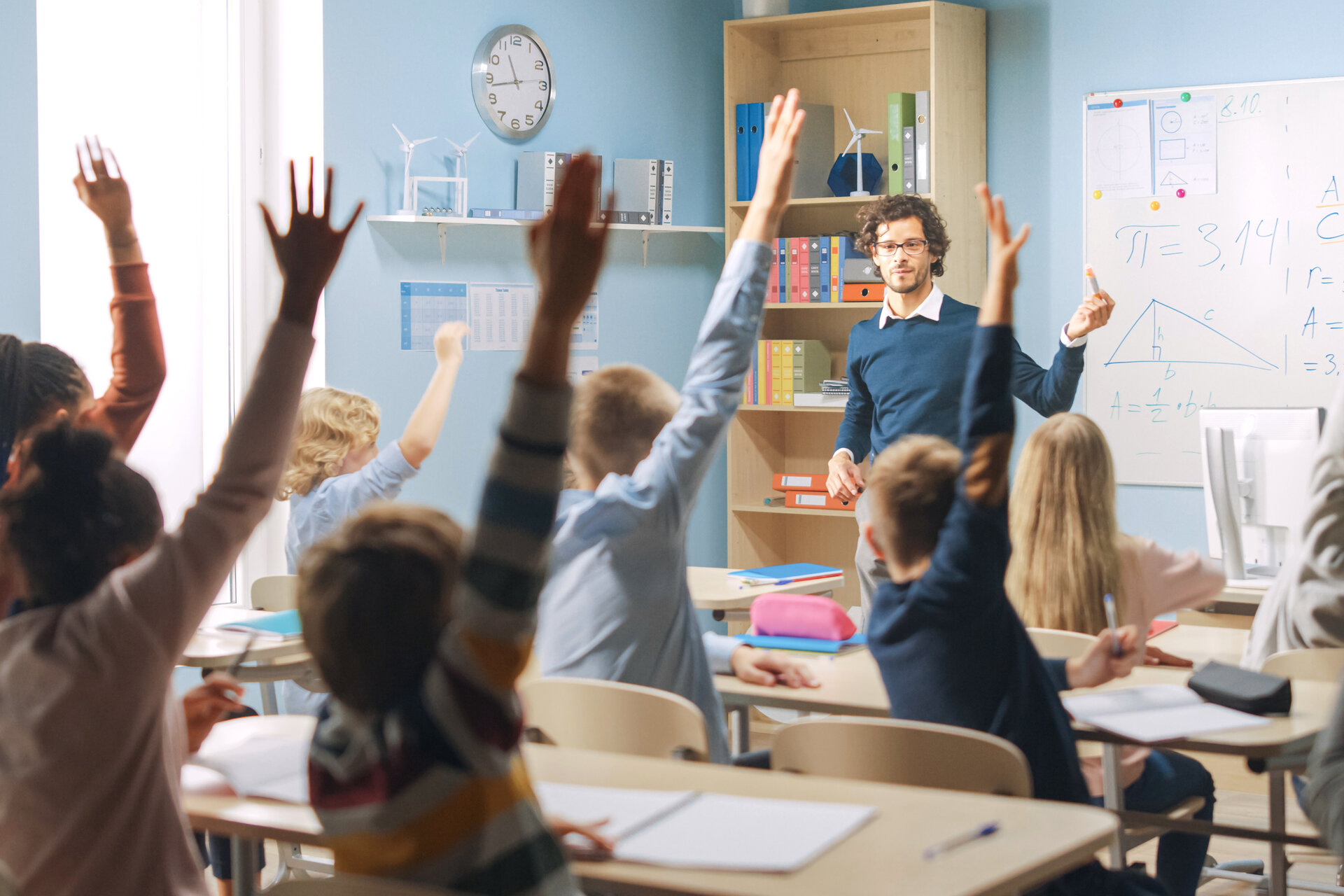 Schüler*innen sitzen in einer Klasse und melden sich.
