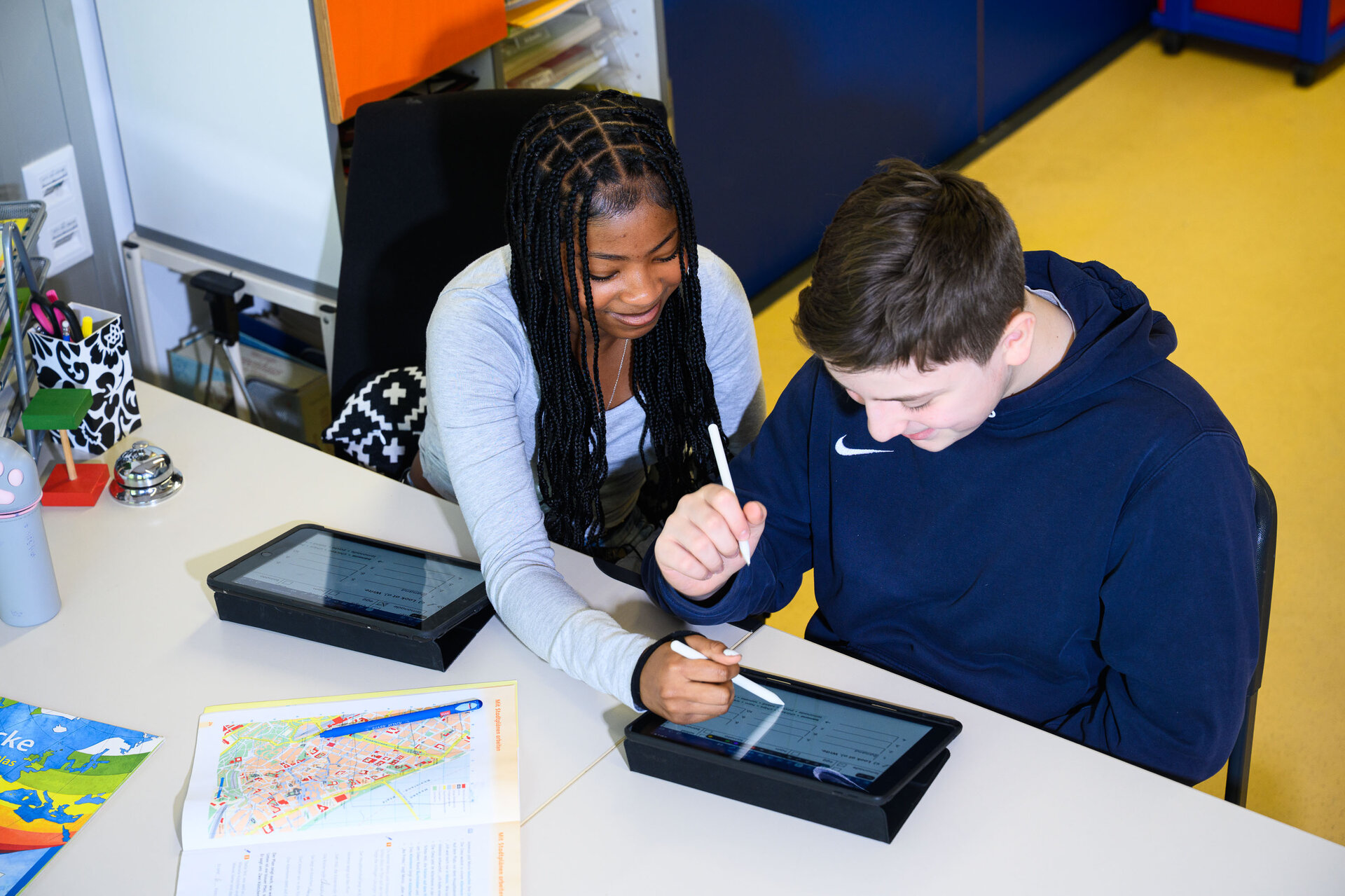 Zwei Jugendgliche arbeiten gemeinsam an Tablets.