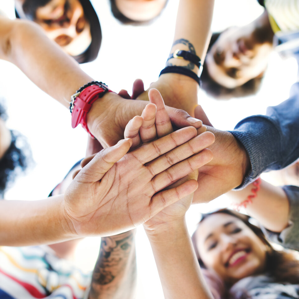 Menschen legen die Hände aufeinander.