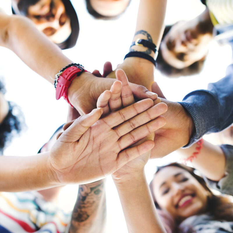 Menschen legen die Hände aufeinander.
