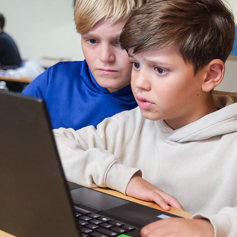 Jugendliche arbeiten gemeinsam an einem Laptop.