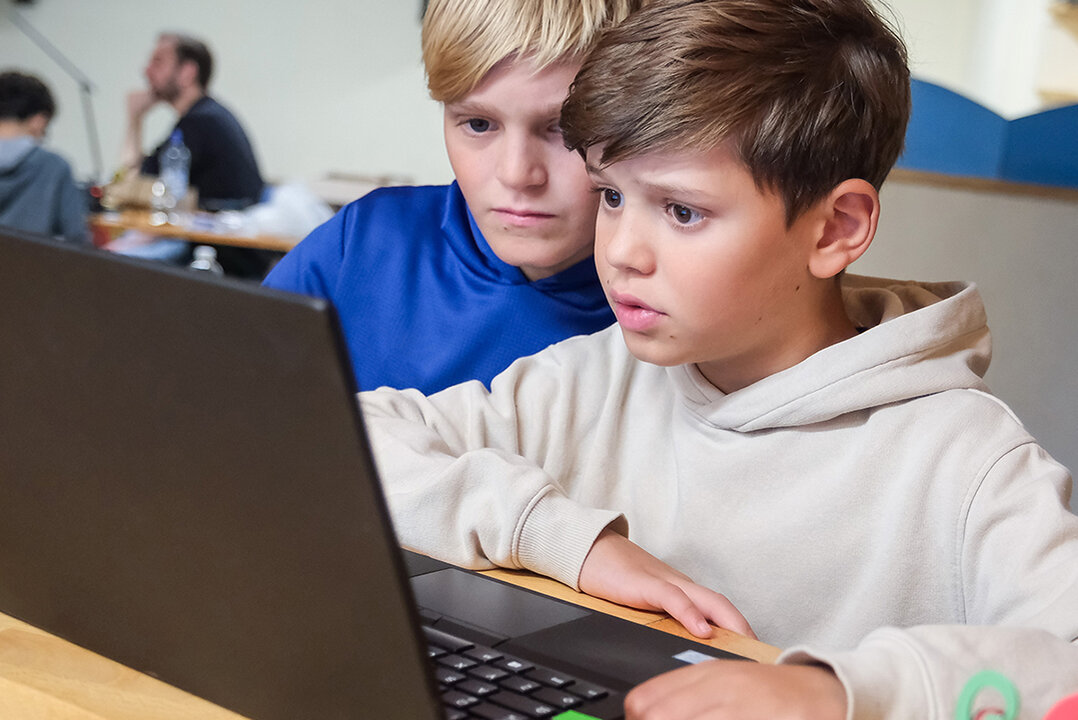 Jugendliche arbeiten gemeinsam an einem Laptop.