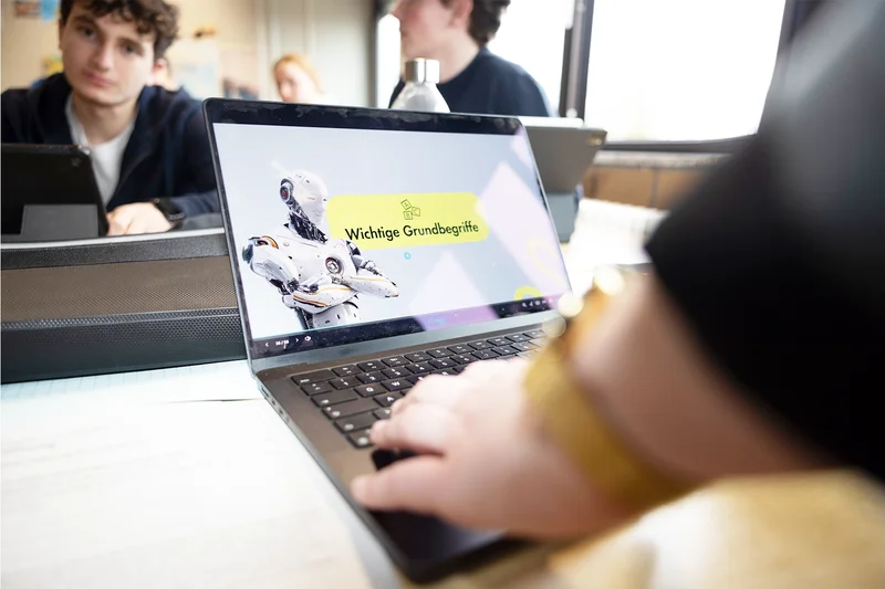 Ein Lehrkraft arbeitet im Klassenraum am Laptop und nutzt eine KI-Anwendung.