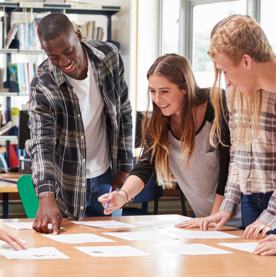 Eine Gruppe Erwachsener steht gemeinsam um einen Arbeitstisch.