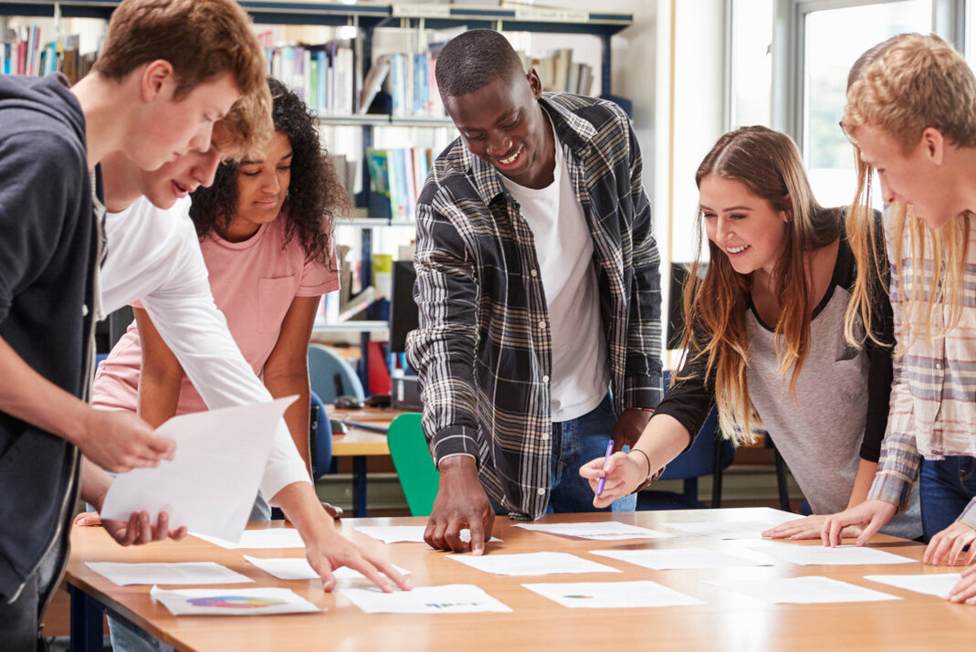 Eine Gruppe Erwachsener steht gemeinsam um einen Arbeitstisch.