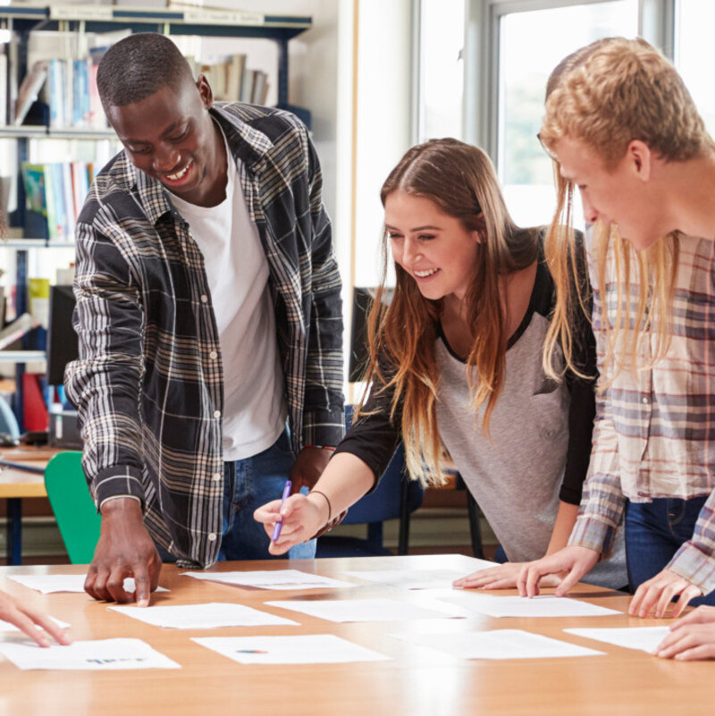 Eine Gruppe Erwachsener steht gemeinsam um einen Arbeitstisch.