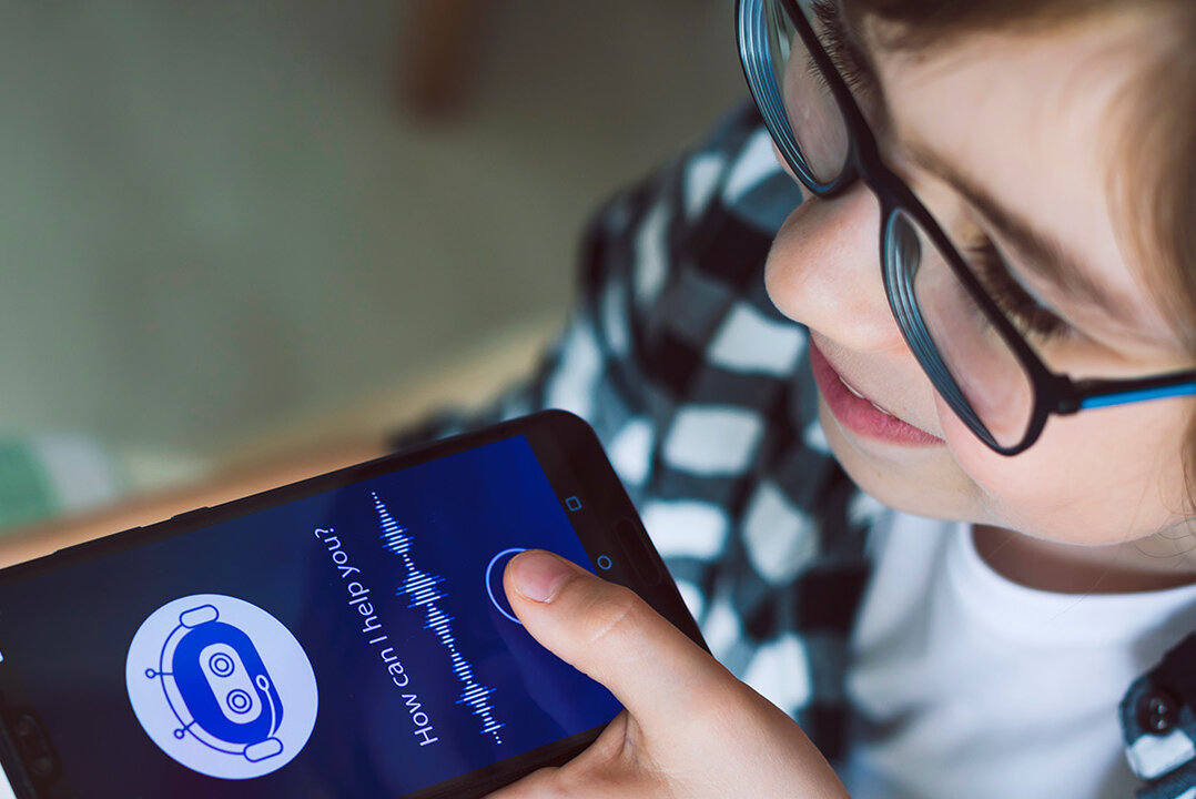 Ein Junge spricht eine Sprachaufnahme in sein Smartphone.