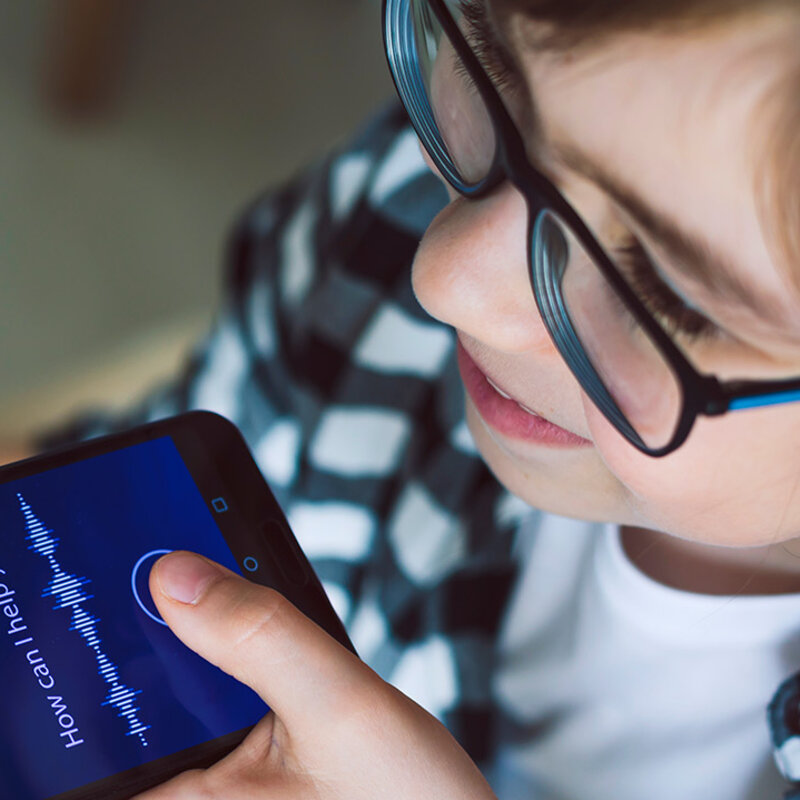 Ein Junge spricht eine Sprachaufnahme in sein Smartphone.