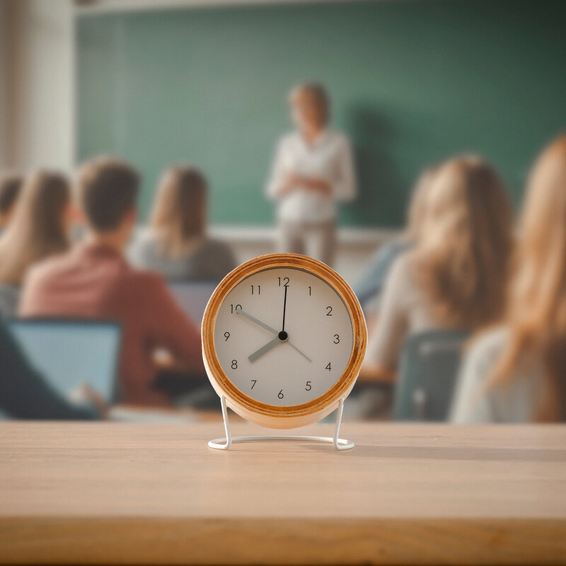 Eine Uhr ist zu sehen, im Hintergrund unscharf ein Klassenzimmer.