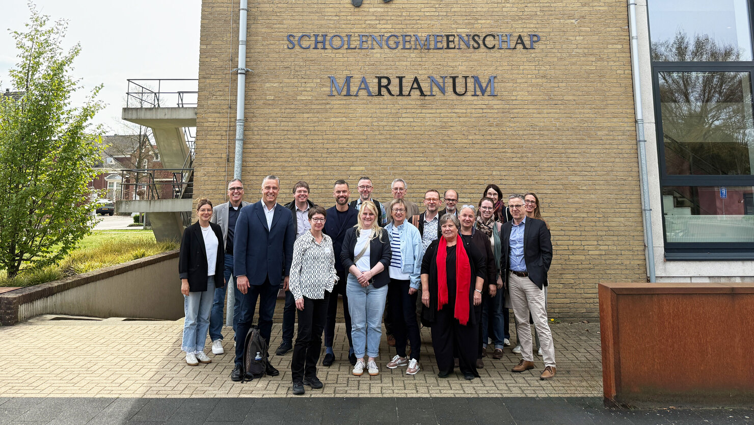 Die Reisegruppe steht gemeinsam vor Scholengemeenschap Marianum in Groenlo, Niederlande.