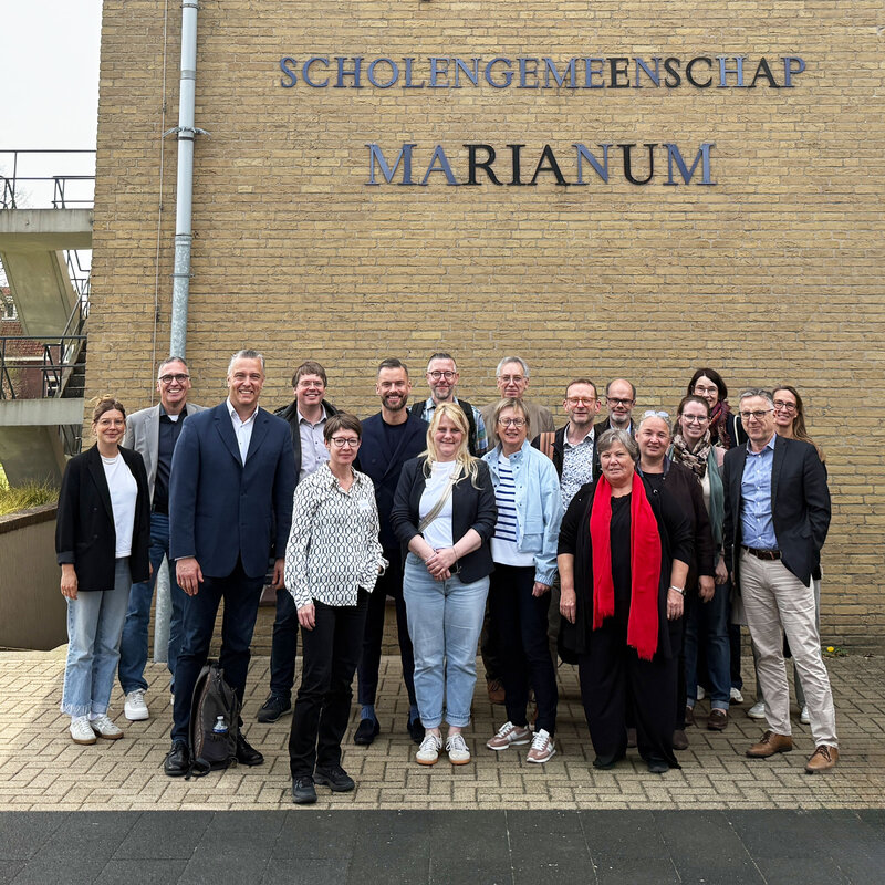 Die Reisegruppe steht gemeinsam vor Scholengemeenschap Marianum in Groenlo, Niederlande.