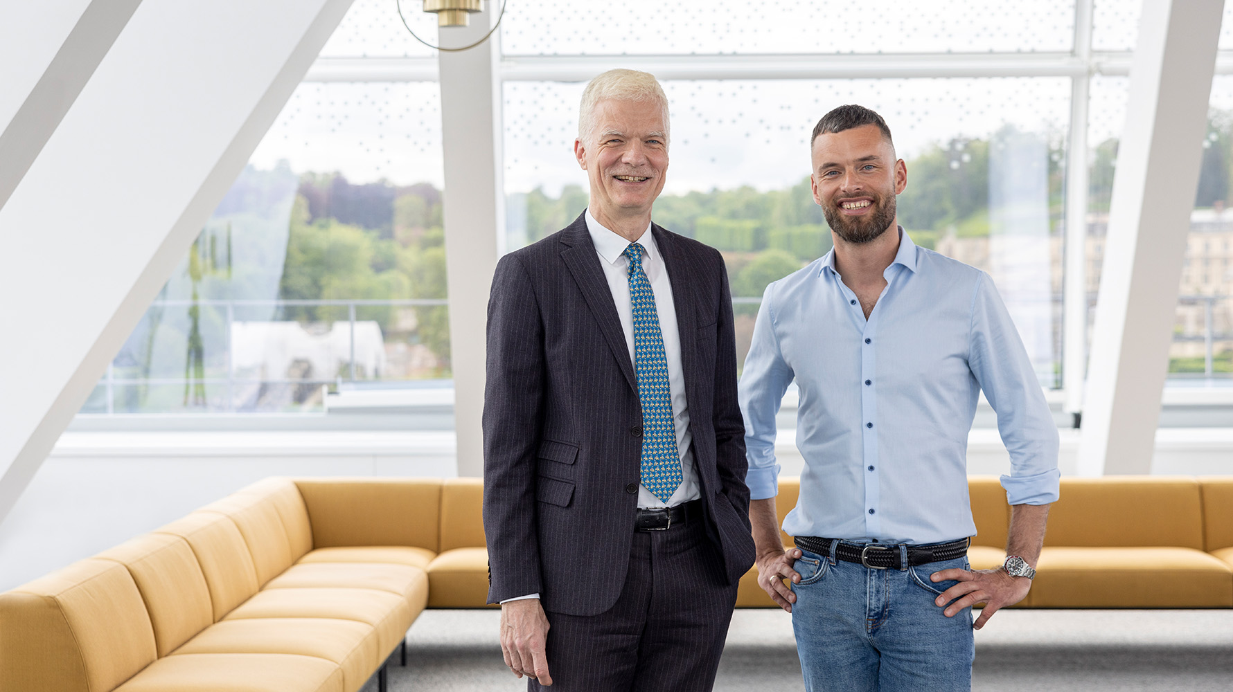Andreas Schleicher und Jacob Chammon stehen vor einem großen Sofa.