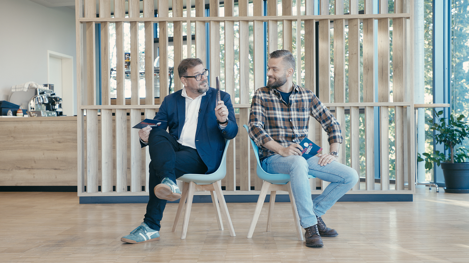 Prof. Dr. Kai Maaz und Jacob Chammon sitzen Rücken an Rücken auf Stühlen und sind einander zugewandt.nd zueinander gewandt.