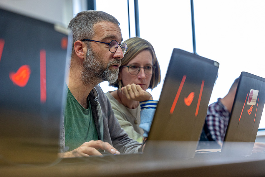 Ältere Erwachsene sitzen vor Laptops