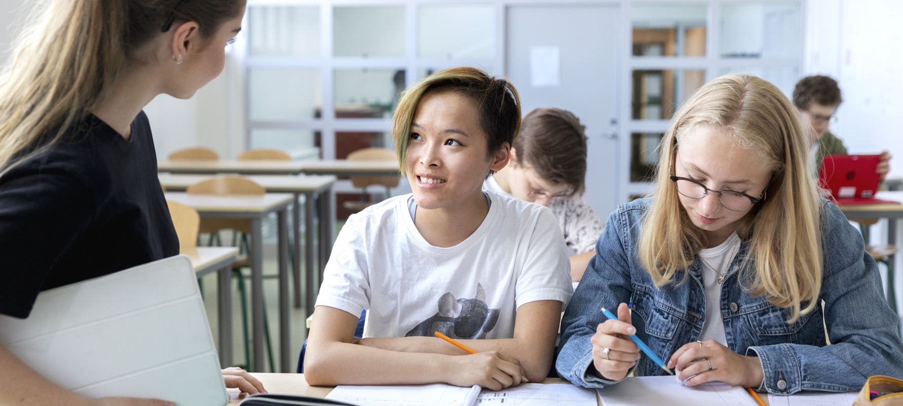 Schülerinnen sprechen im Klassenzimmer mit ihrer Lehrerin