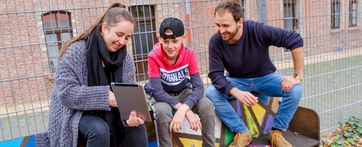 Pädagogen erklären einem Jugendlichen etwas auf dem Tablet-PC