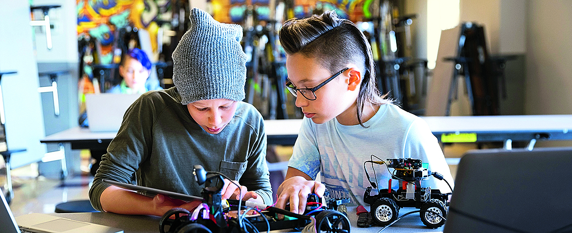 Two teenager building a robot together