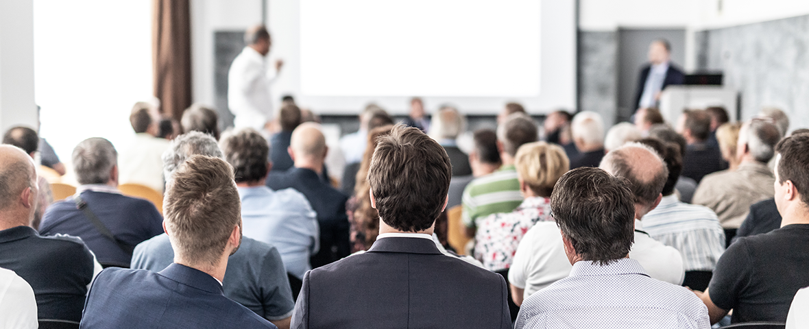 Das Bild zeigt Konferenzteilnehmer in der Rückenansicht.