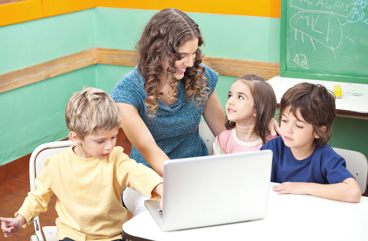 Lehrerin unterrichtet Grundschulinder am Laptop