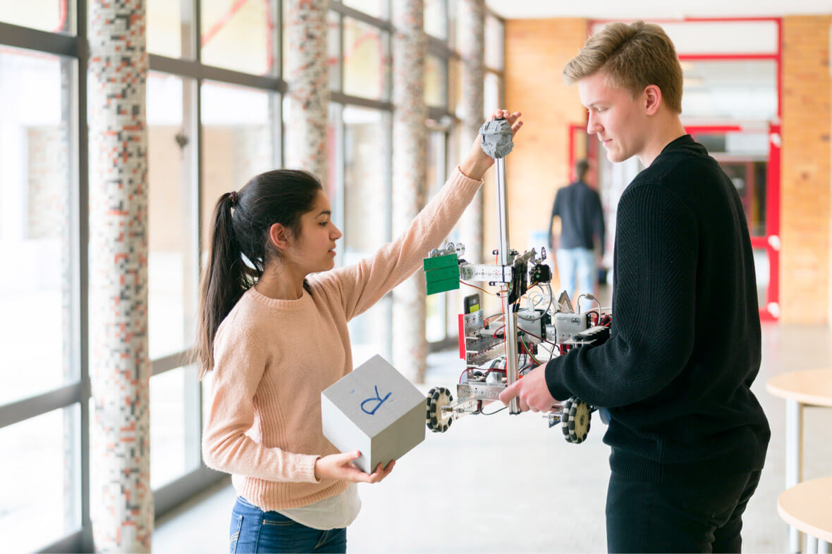 Schüler mit einem selbstgebauten Roboter in der Hand