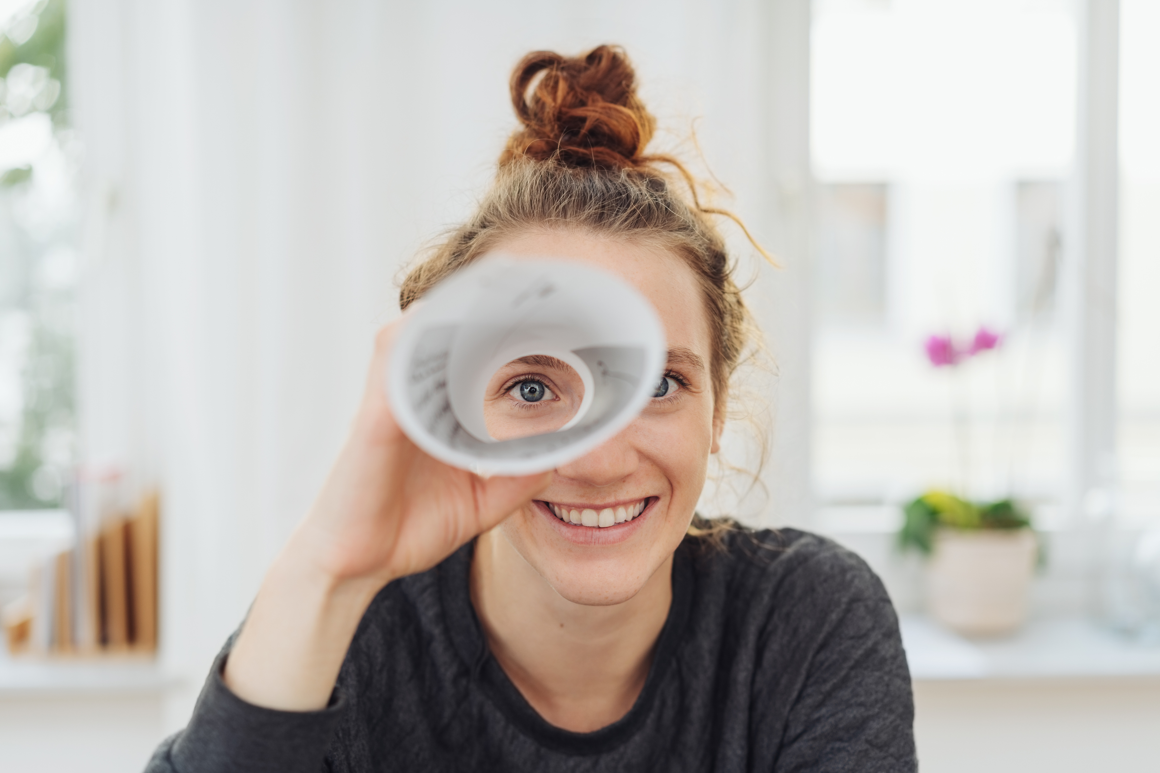 Woman looking trough a rolled paper