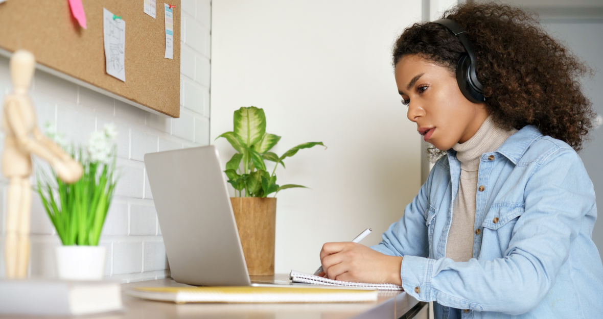Frau sitzt mit Headset vor Laptop