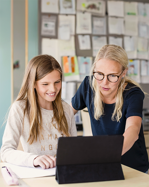 Ein Mädchen und eine erwachsene Frau schauen gemeinsam auf ein Tablet.