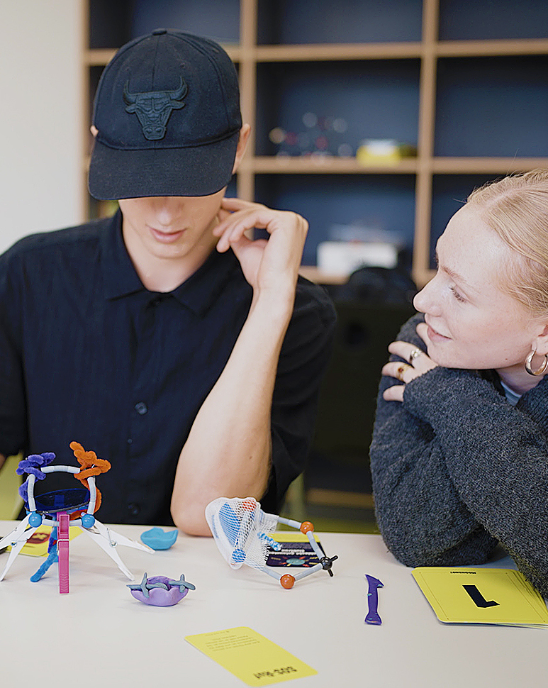 Drei Jugendliche sitzen an einem Tisch und arbeiten kreativ.
