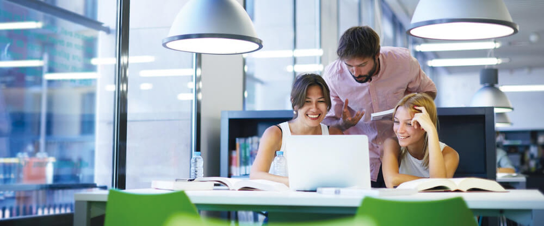Three journalists behind a laptop computer in a modern office