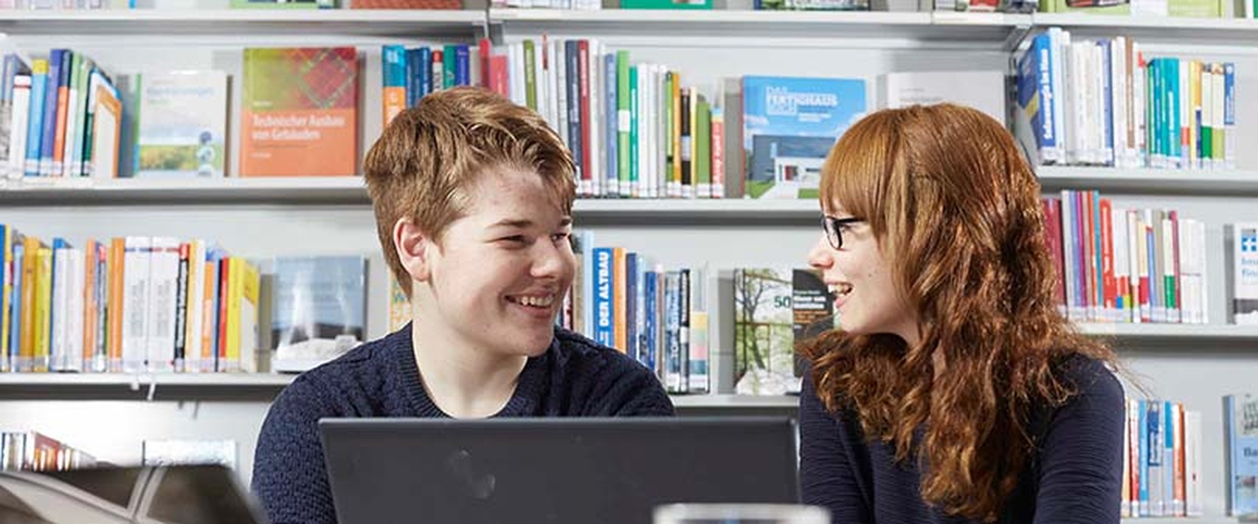 Zwei Bibliotheksbesucher arbeiten an einem Laptop