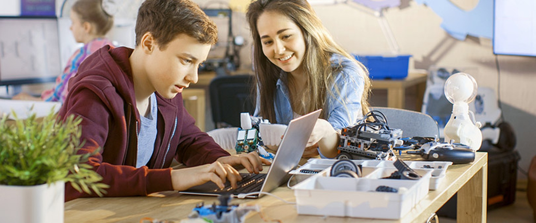Ein Schüler und eine Schülerin arbeiten mit digitalen Geräten.