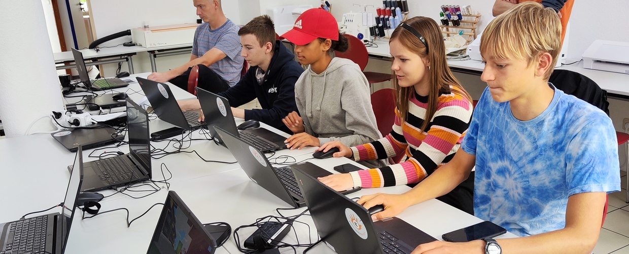 Kinder sitzen vor Laptops.