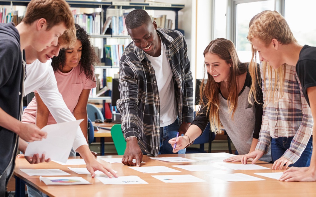 Lehrkraft und Schüler arbeiten an Computern und Laptops.