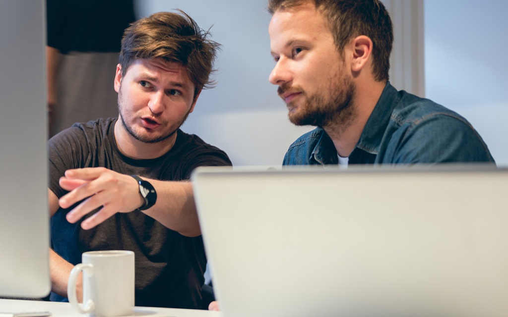 Zwei Nachwuchsforscher sitzen am Rechner und diskutieren.