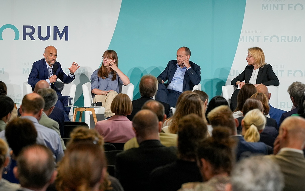 Menschen sitzen vor einer Bühne beim Nationalen MINT Forum.