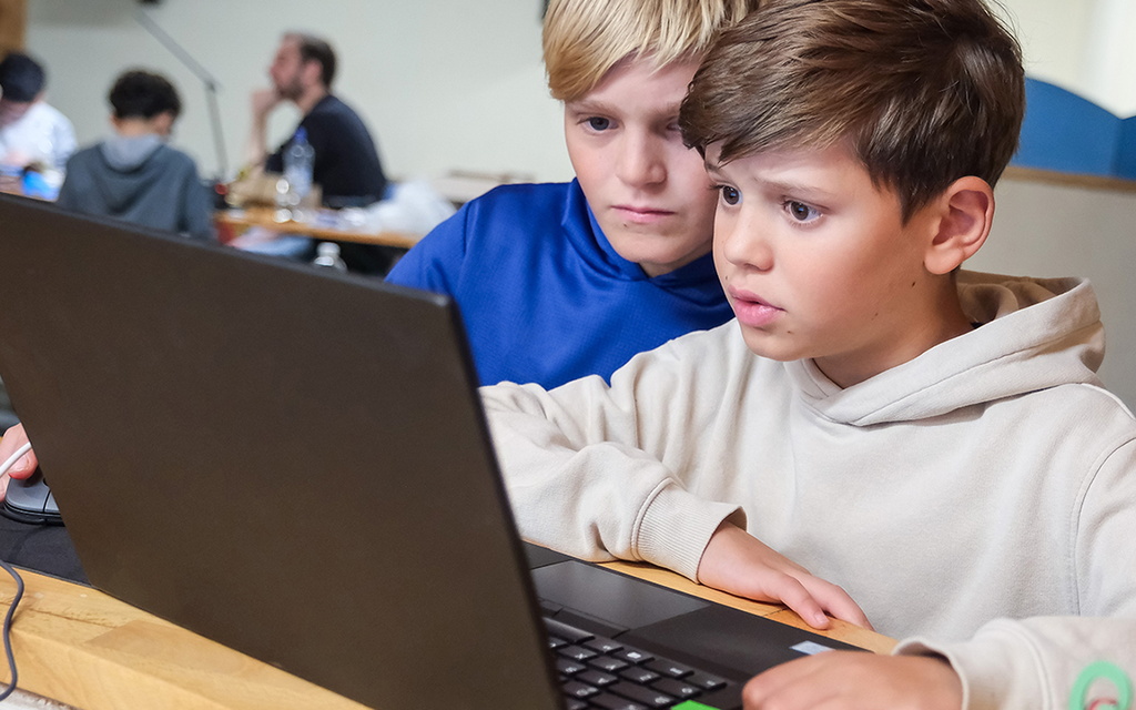 Zwei Schüler sitzen vor einem Laptop.