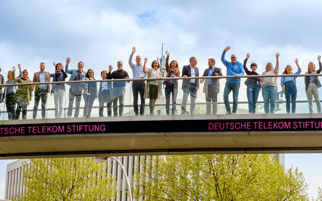 Die Mitarbeiterinnen und Mitarbeiter der Telekom-Stiftung stehen auf einer Brücke.