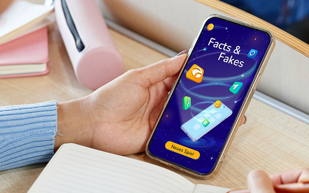 Eine Person hat ein Smartphone in der Hand. Auf dem Smartphone läuft das Spiel Facts & Fakes.