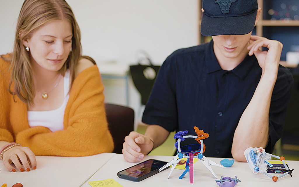 Drei Jugendliche sitzen an einem Tisch und arbeiten kreativ.