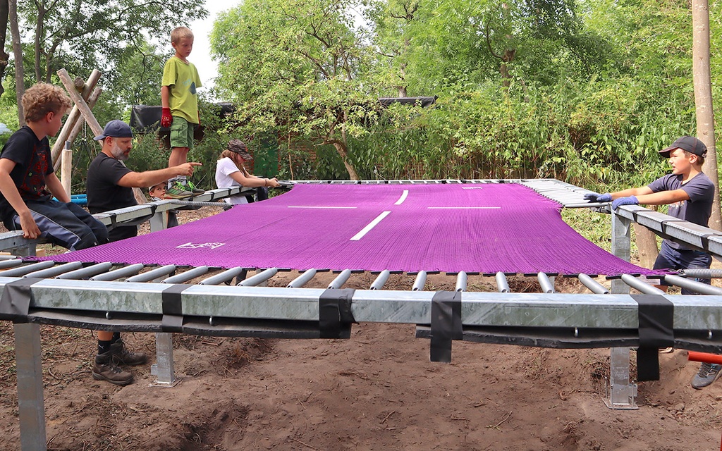 Das Bild zeigt Kinder, die an einem Trampolin bauen.