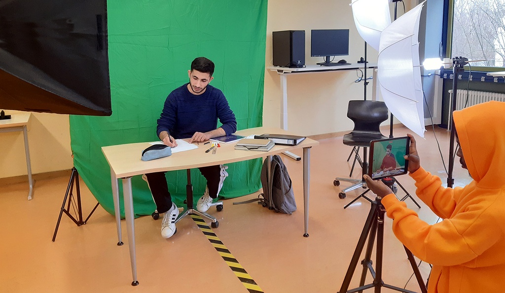 Jugendliche nehmen ein Video vor einem Greenscreen auf.
